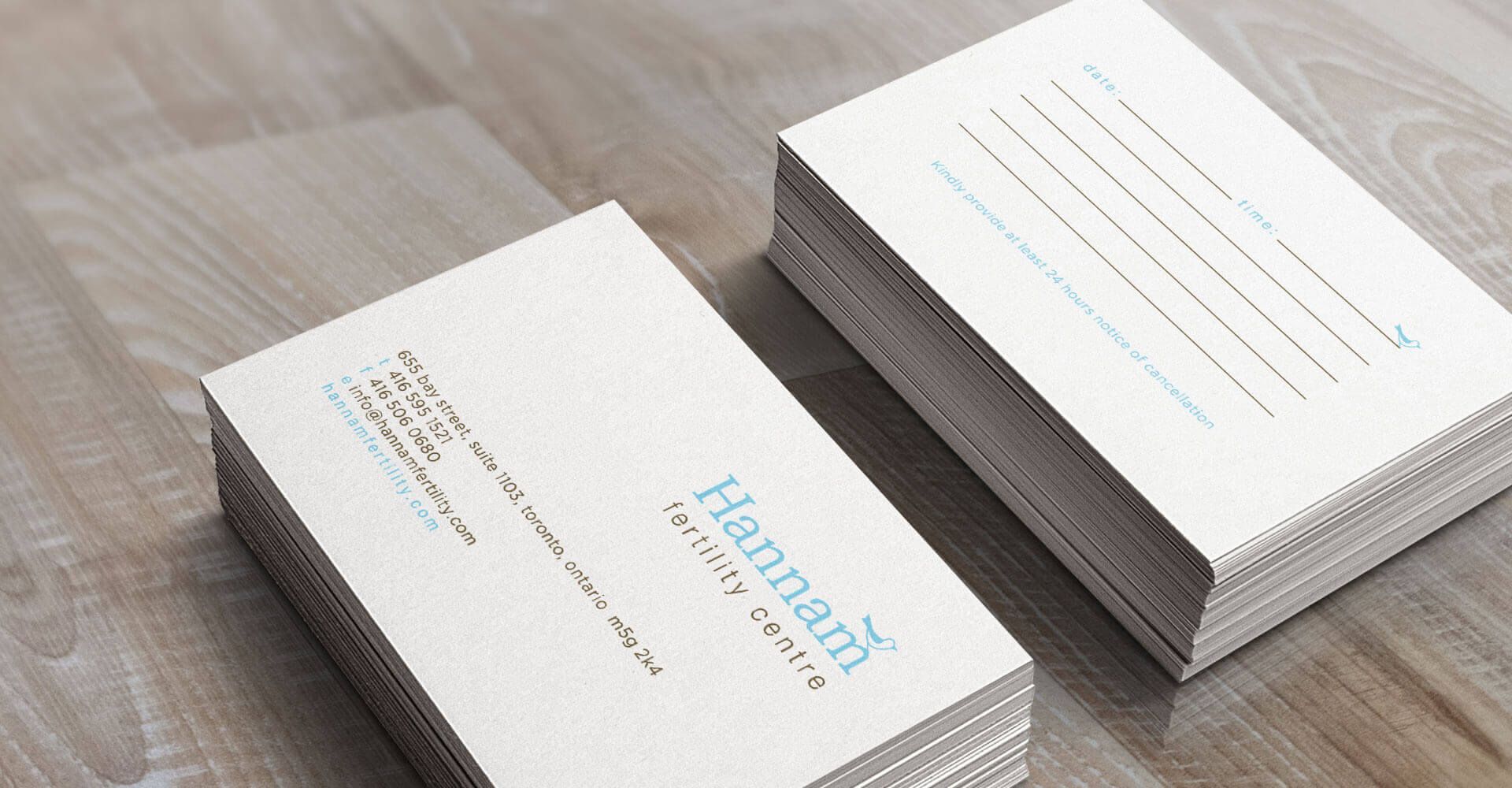 Two business cards are stacked on top of each other on a wooden table.