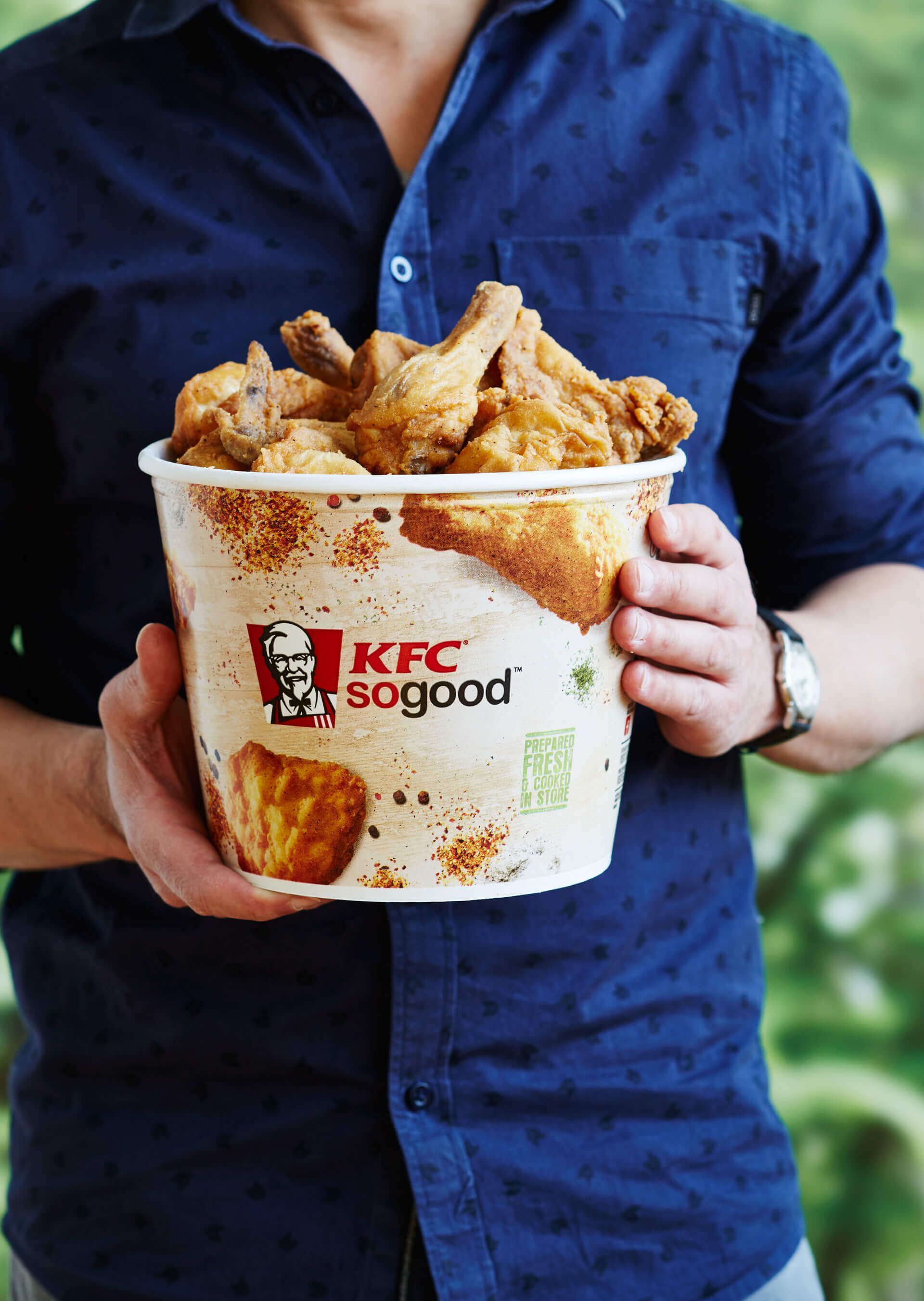 A man is holding a bucket of fried chicken.