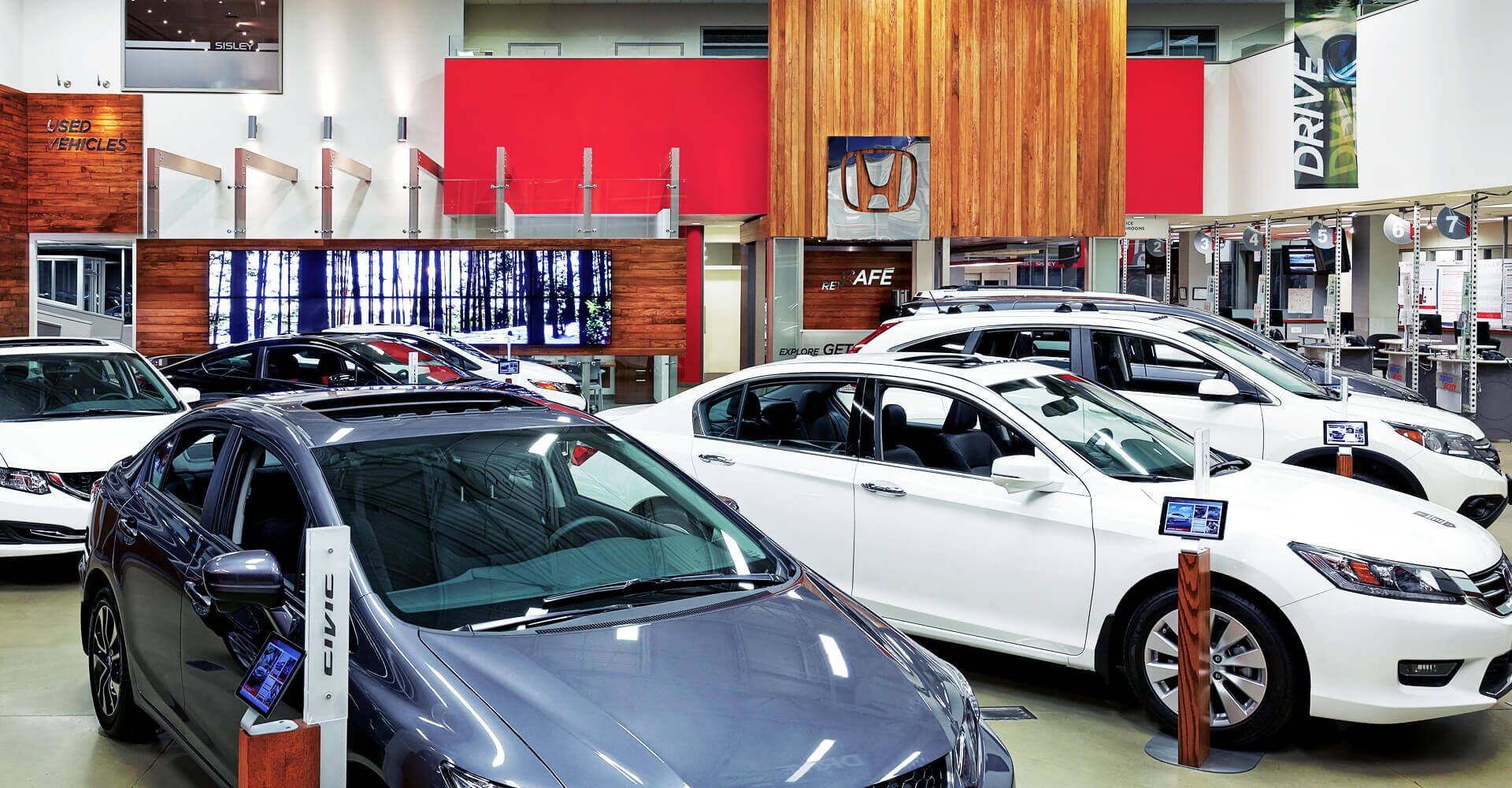 A row of cars are parked in a showroom.