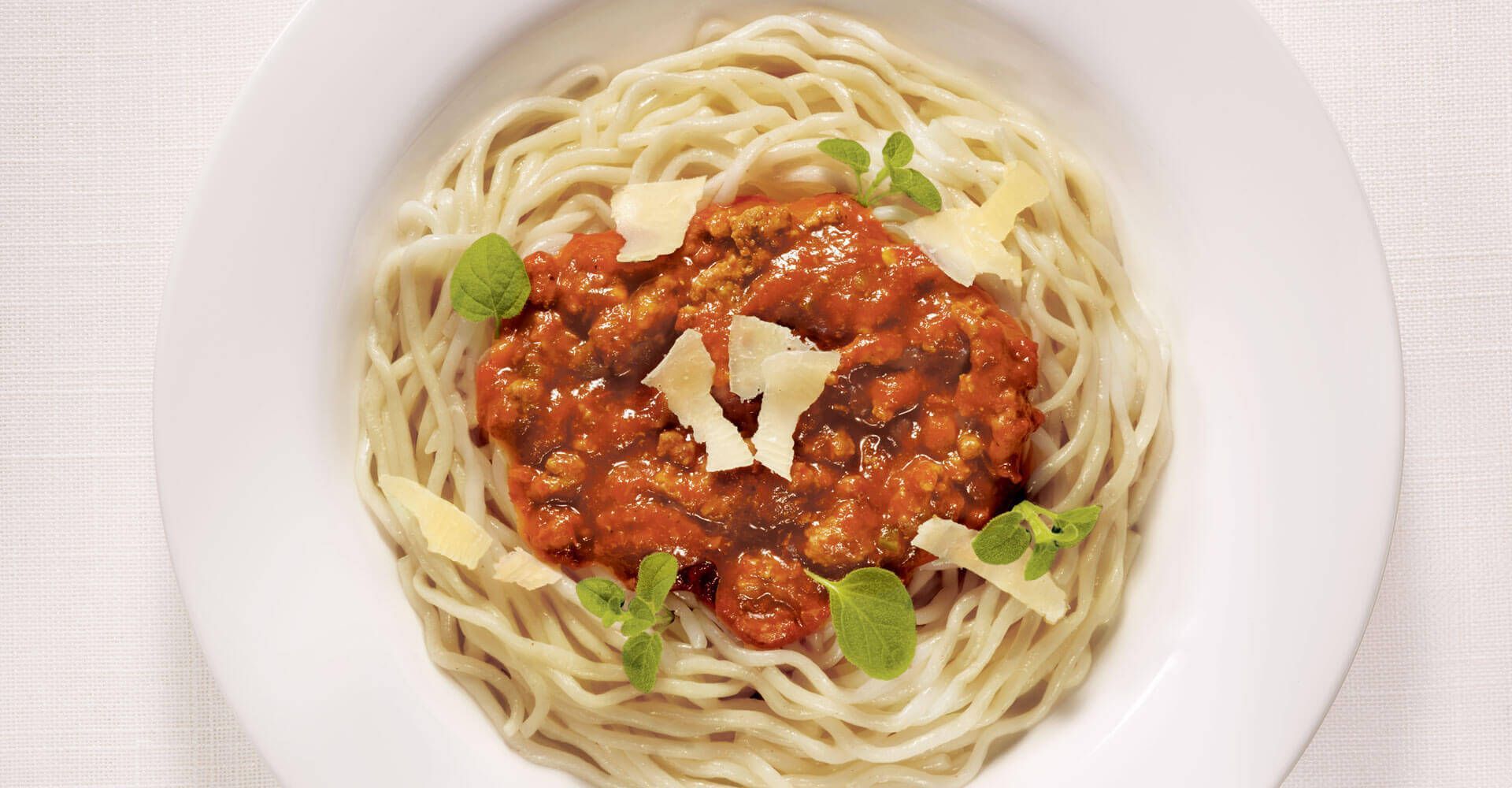 A white plate topped with spaghetti and meat sauce.