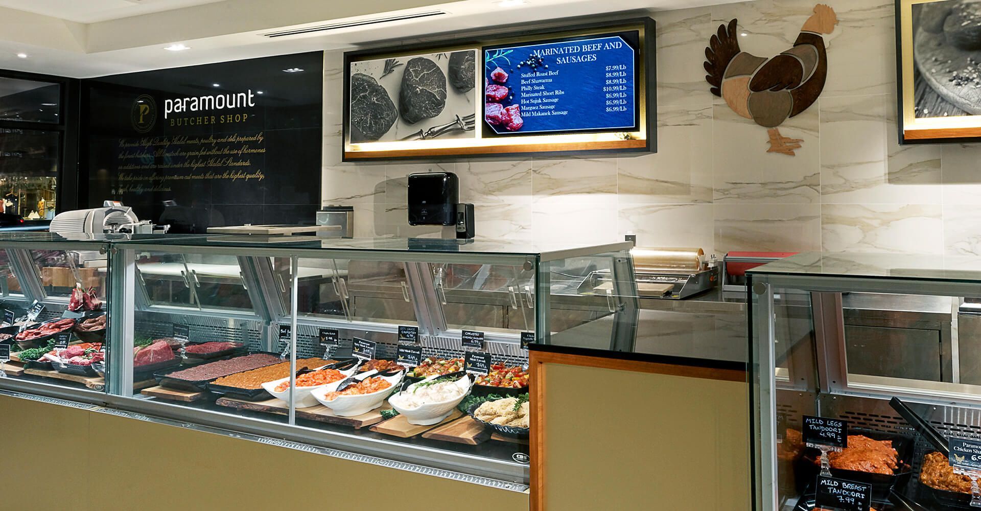 A butcher shop with a chicken on the wall above the counter.