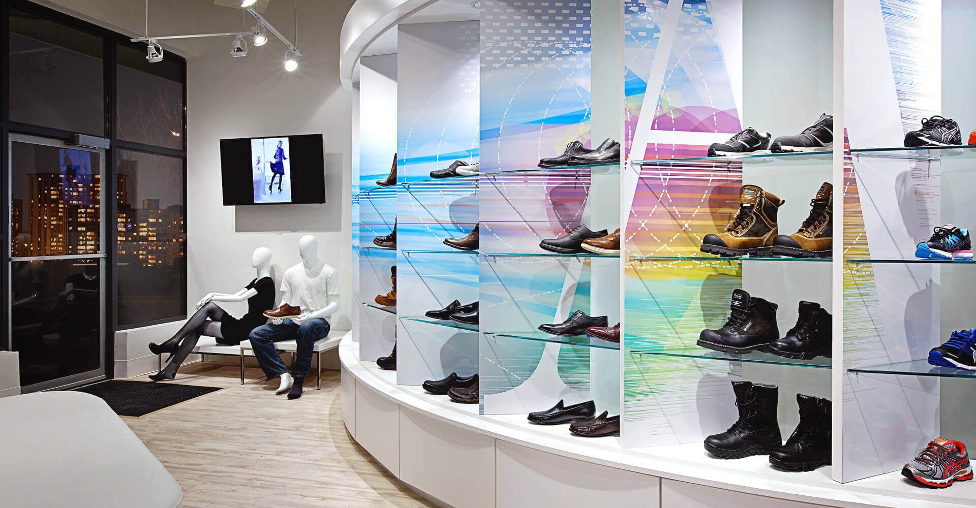A man and woman are sitting on a bench in a shoe store.