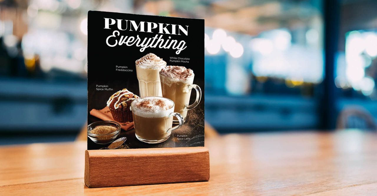 A pumpkin everything sign is sitting on a wooden table.