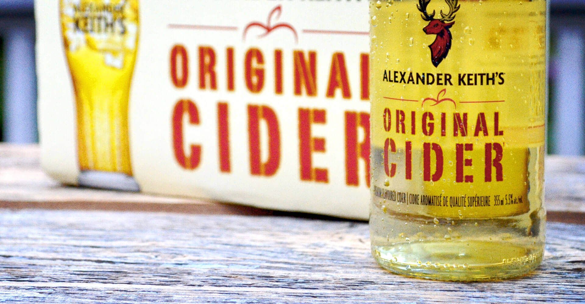 A bottle of alexander keith 's original cider is sitting on a wooden table.