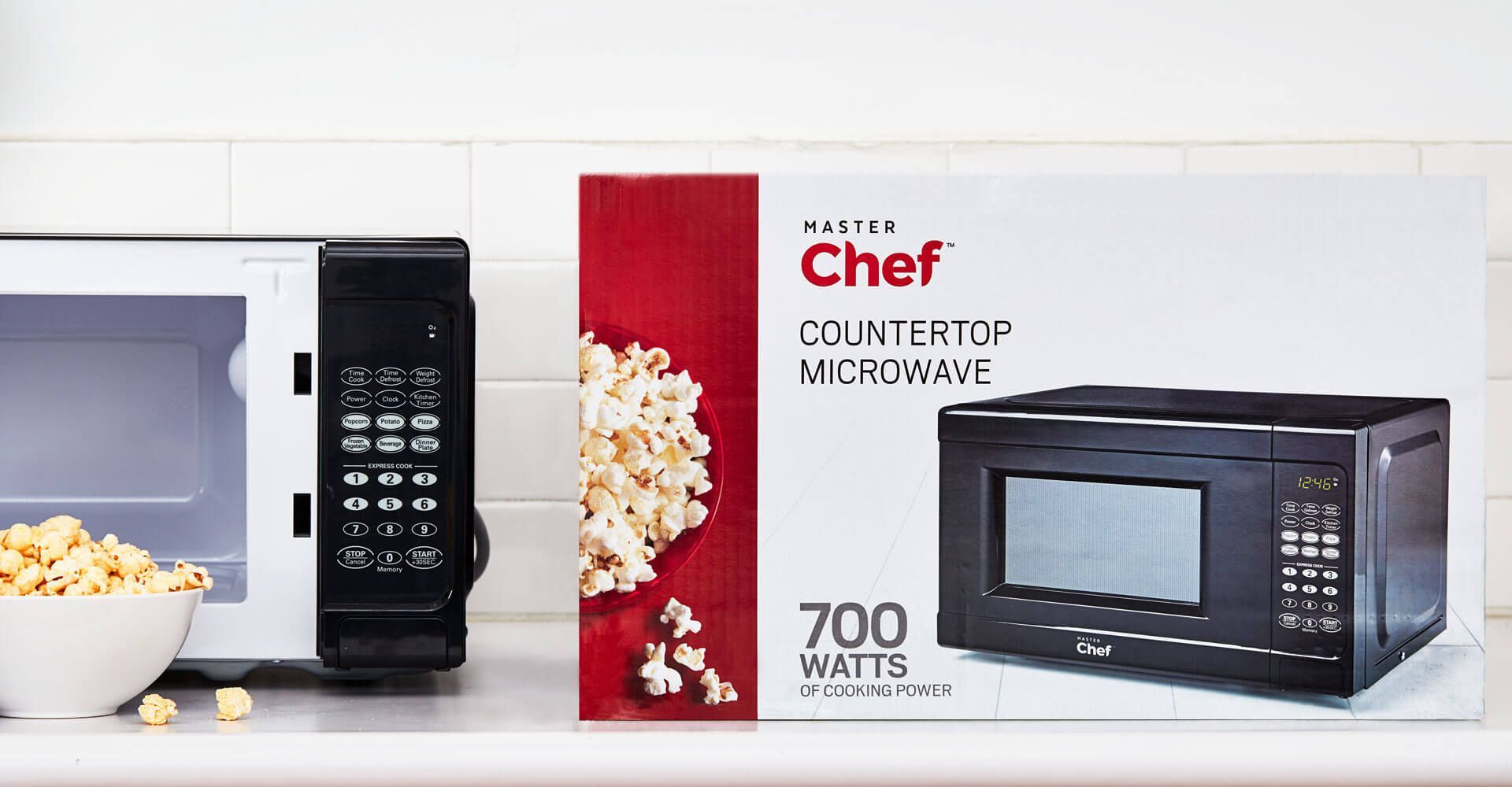 A chef countertop microwave with a bowl of popcorn next to it