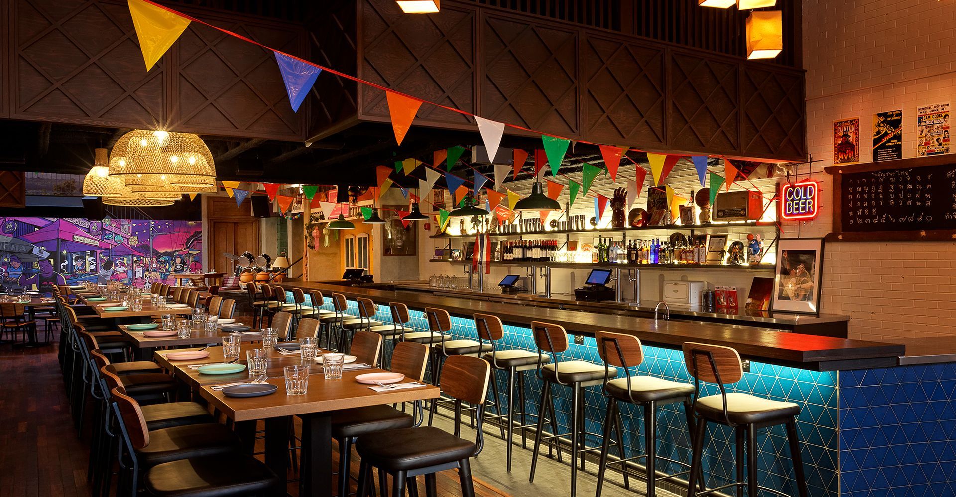 A restaurant with tables and chairs and a long bar.