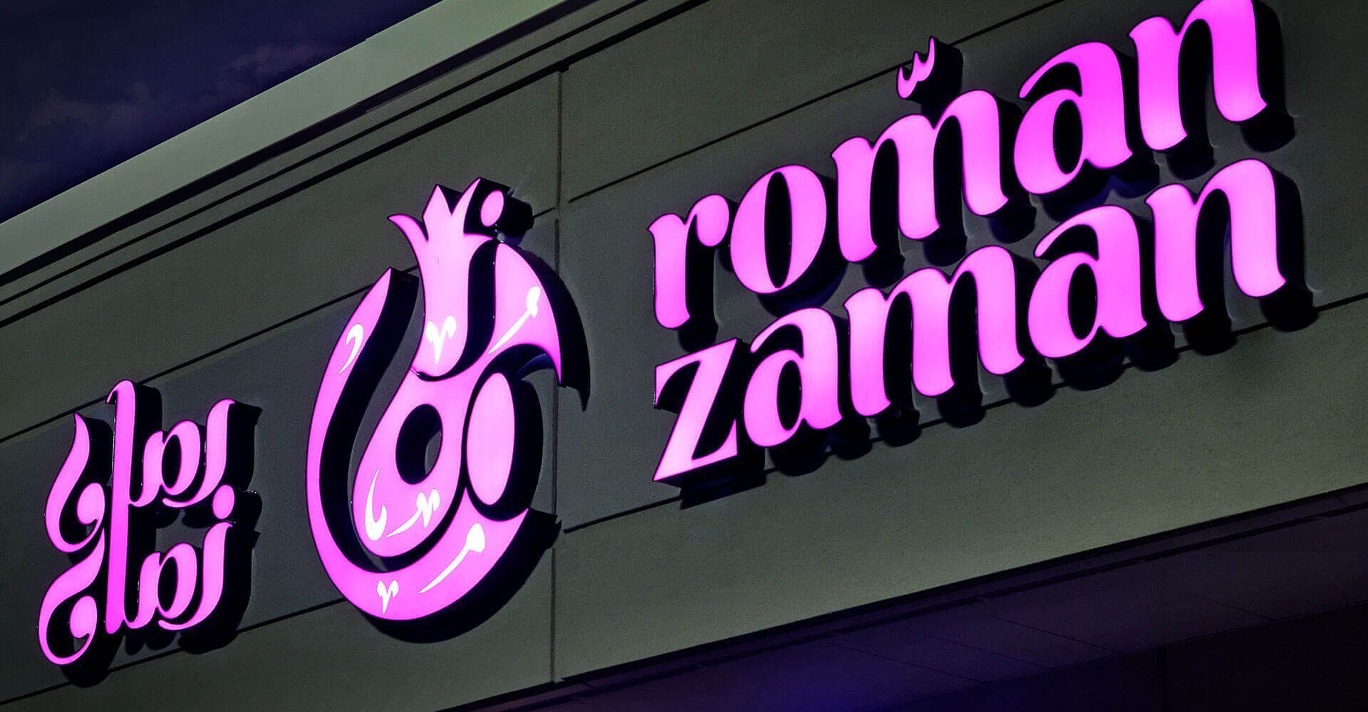 A sign for roman zaman is lit up at night