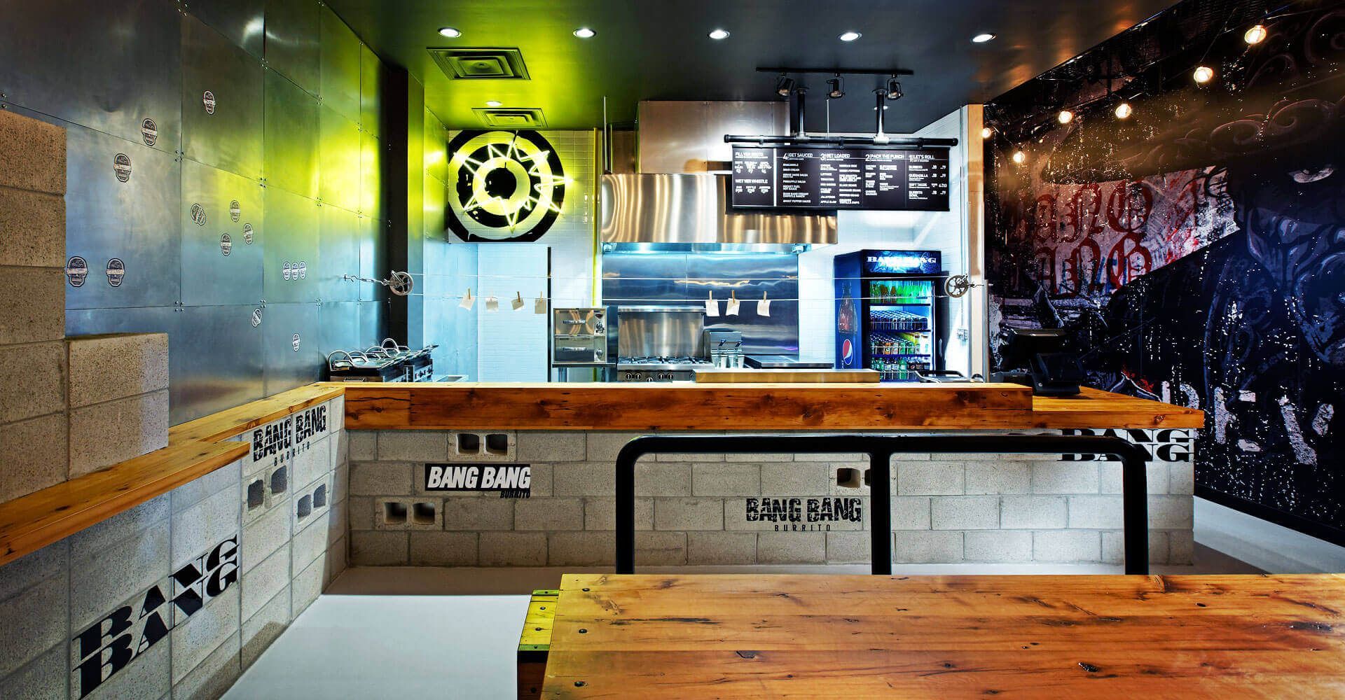 A restaurant with a wooden table and benches and a refrigerator.