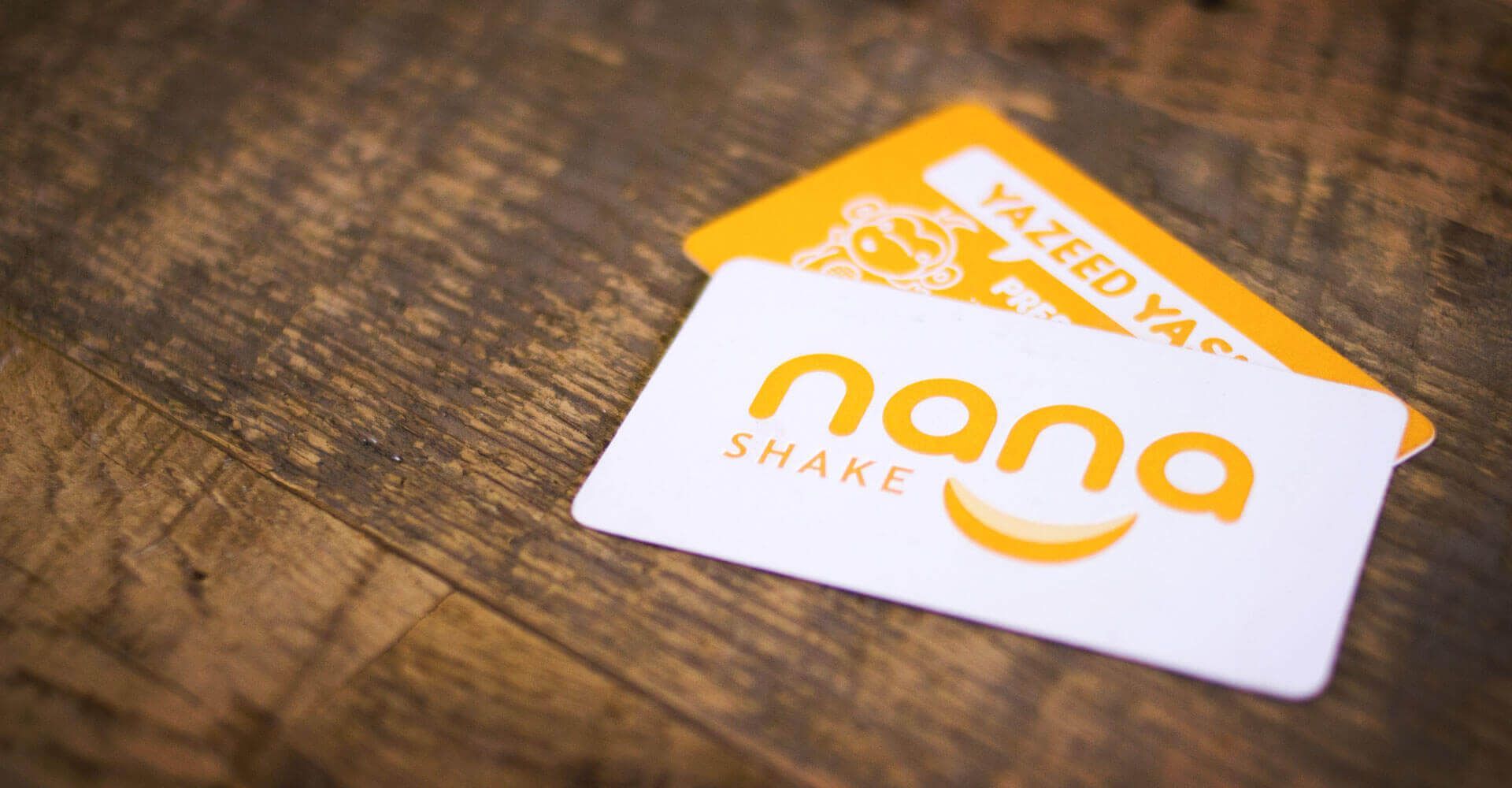 Two nana shake cards are sitting on a wooden table.