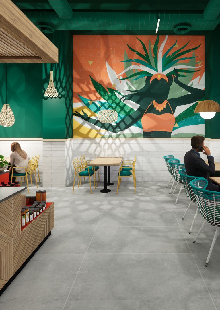 A man is sitting at a table in a restaurant with a large mural on the wall.