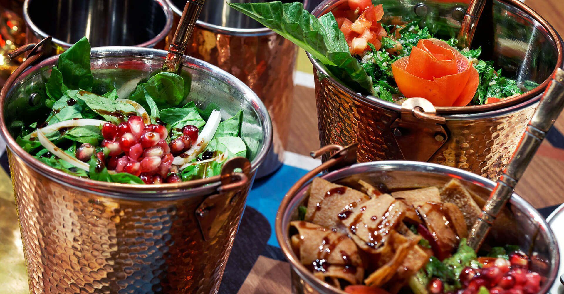 A table topped with copper buckets filled with different types of food.