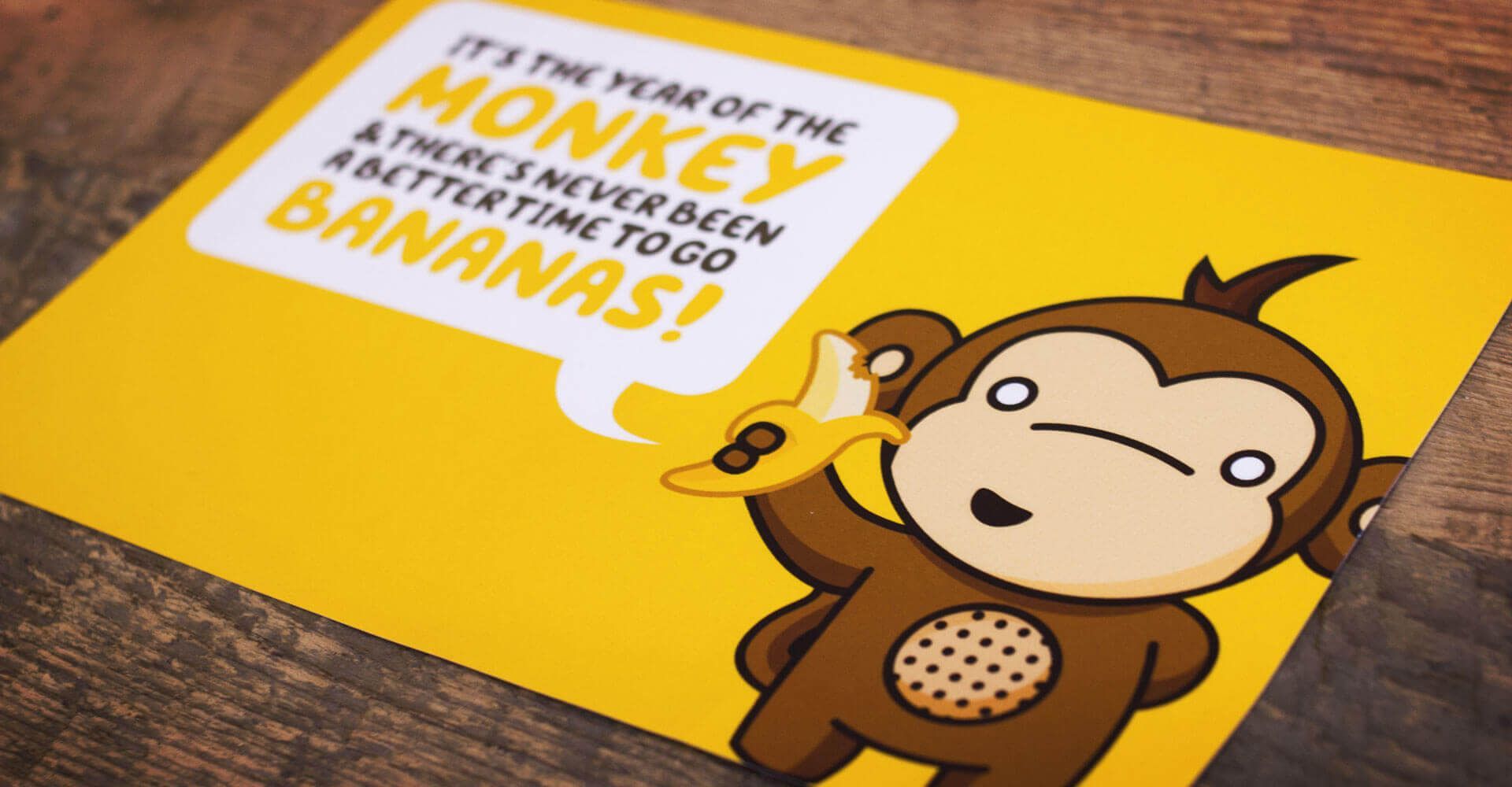 A monkey holding a banana with a speech bubble that says it 's the year of the monkey