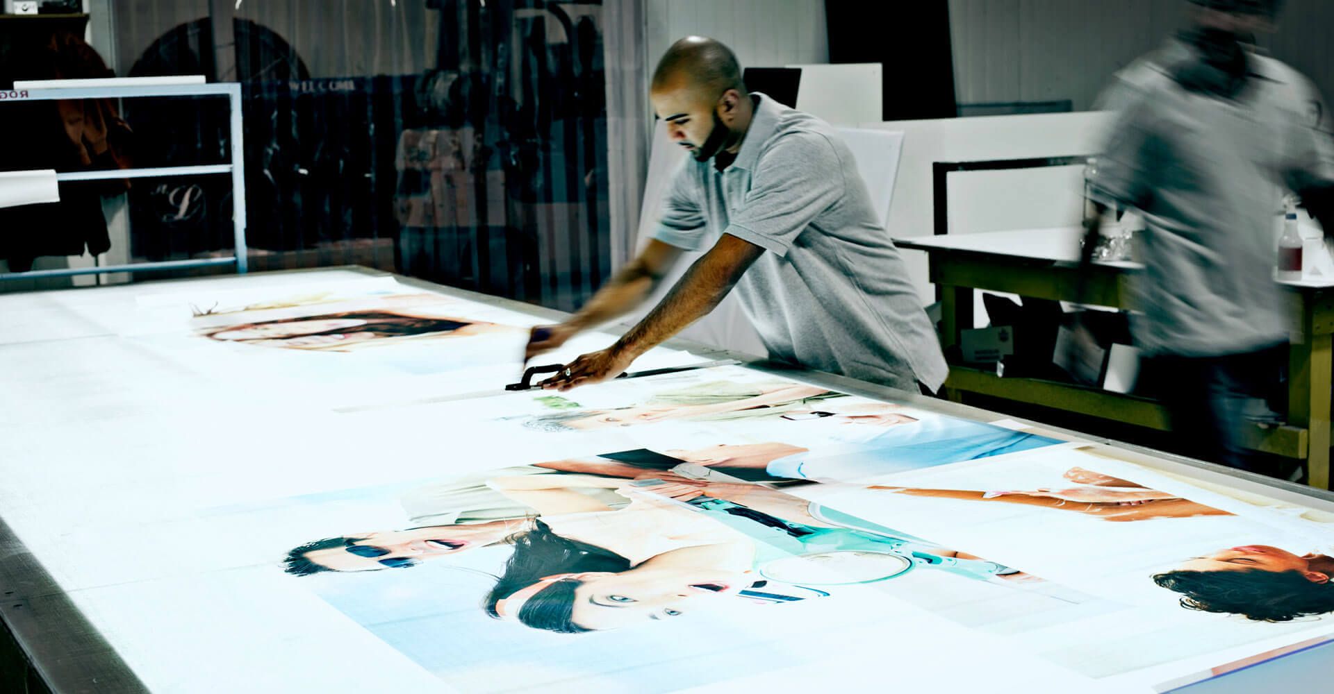 A man is working on a large painting on a table.
