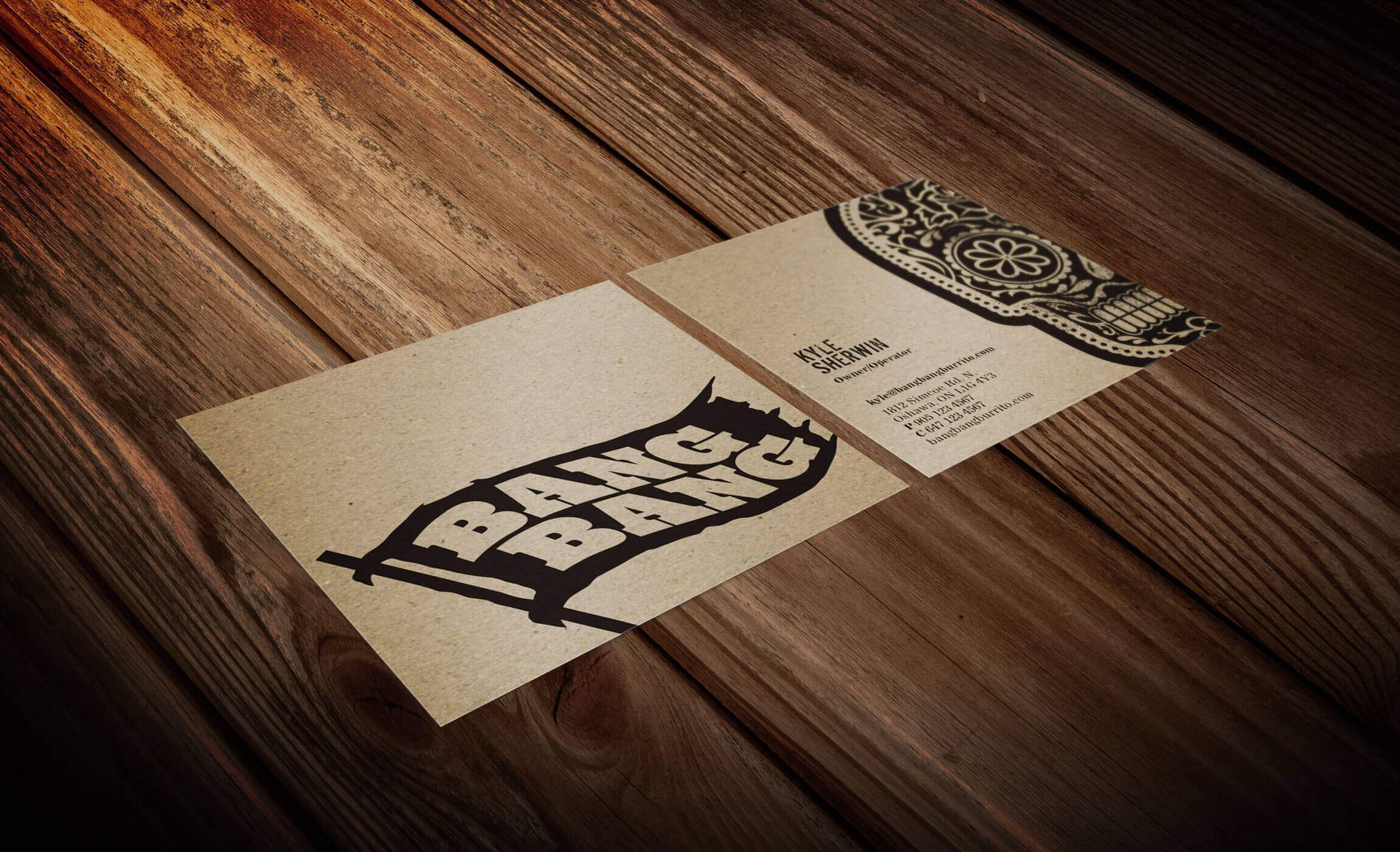 Two business cards are laying on a wooden table.