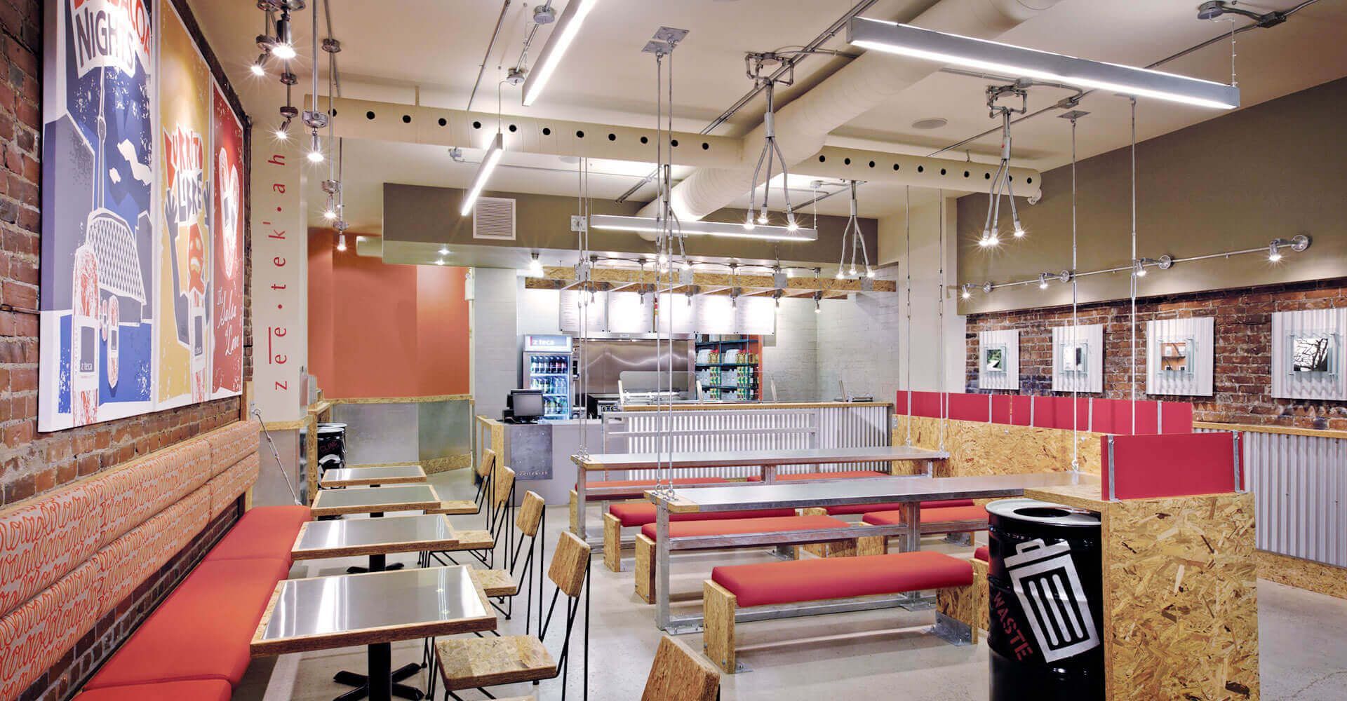 A restaurant with tables and benches and a trash can