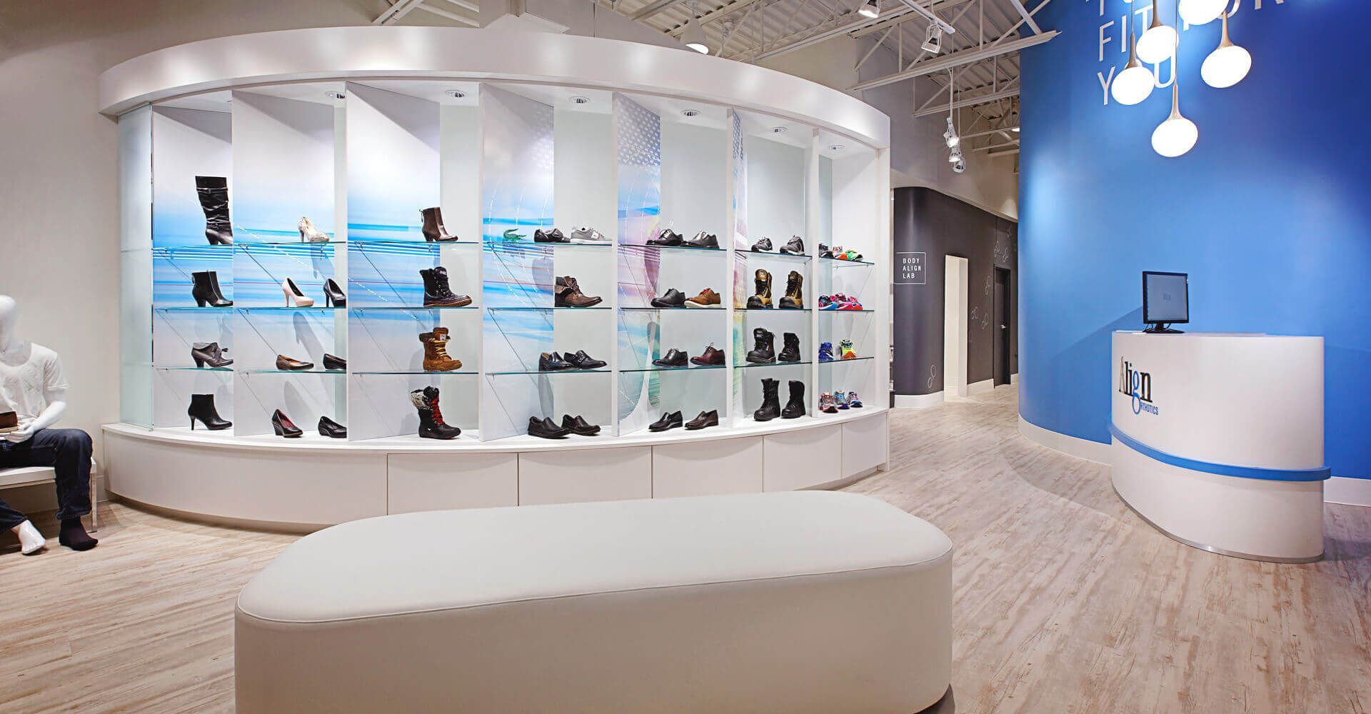 A man is sitting on a bench in a shoe store.
