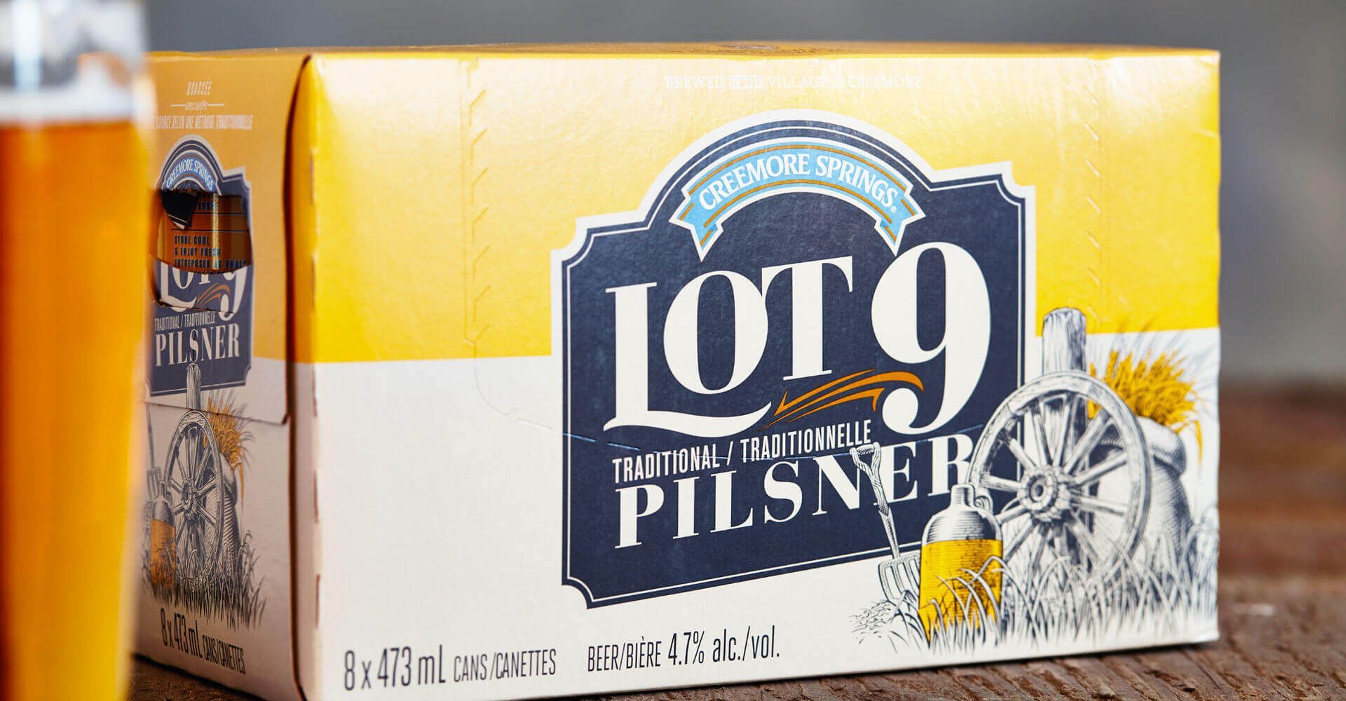 A box of lot 9 pilsner beer is sitting on a wooden table.