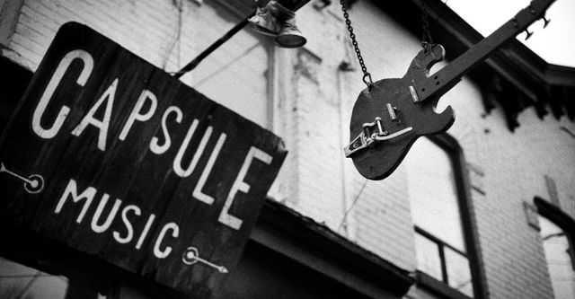 A black and white photo of a sign for capsule music