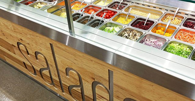 A salad bar with lots of toppings and a sign that says salad.