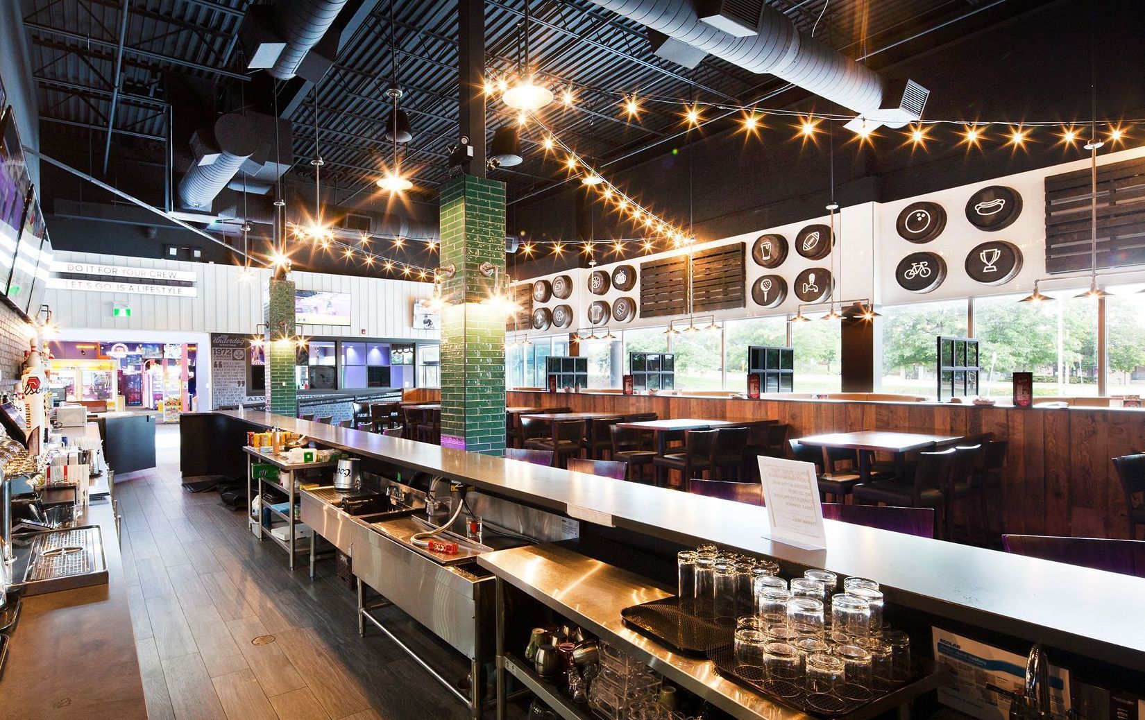 The inside of a restaurant with a long bar and tables.