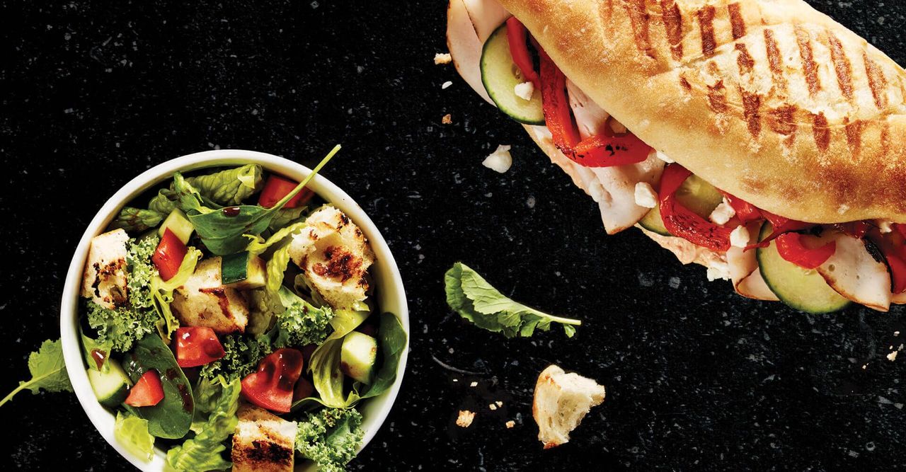A sandwich next to a bowl of salad on a table