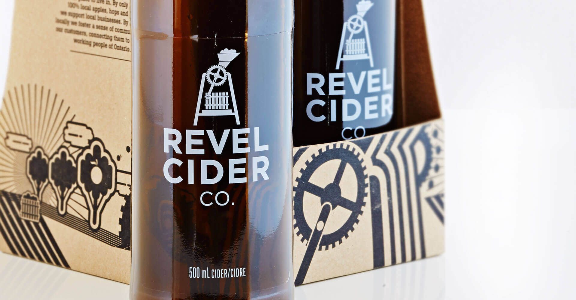 Two bottles of revel cider co. are in a cardboard box