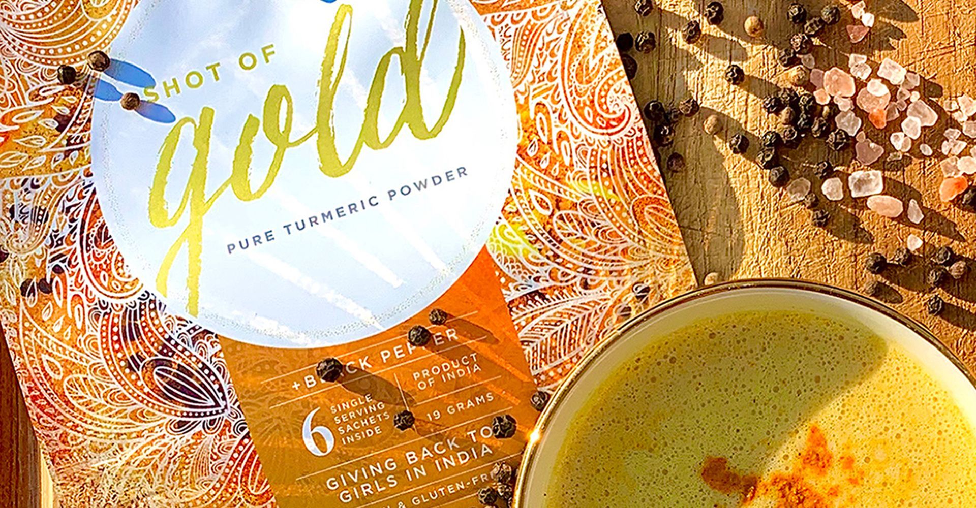 There is a bowl of gold tea next to a book.