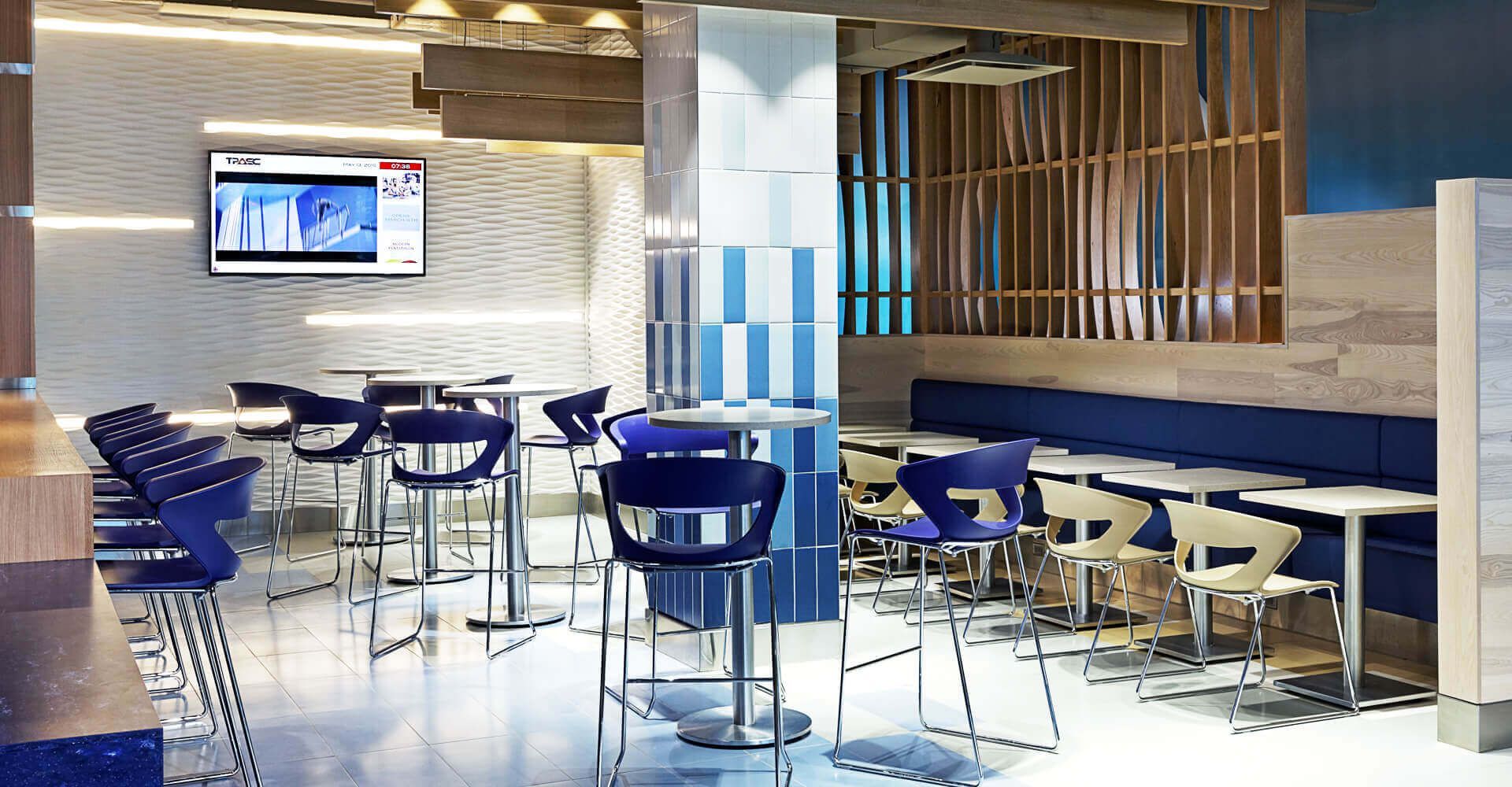 A restaurant with tables and chairs and a television on the wall