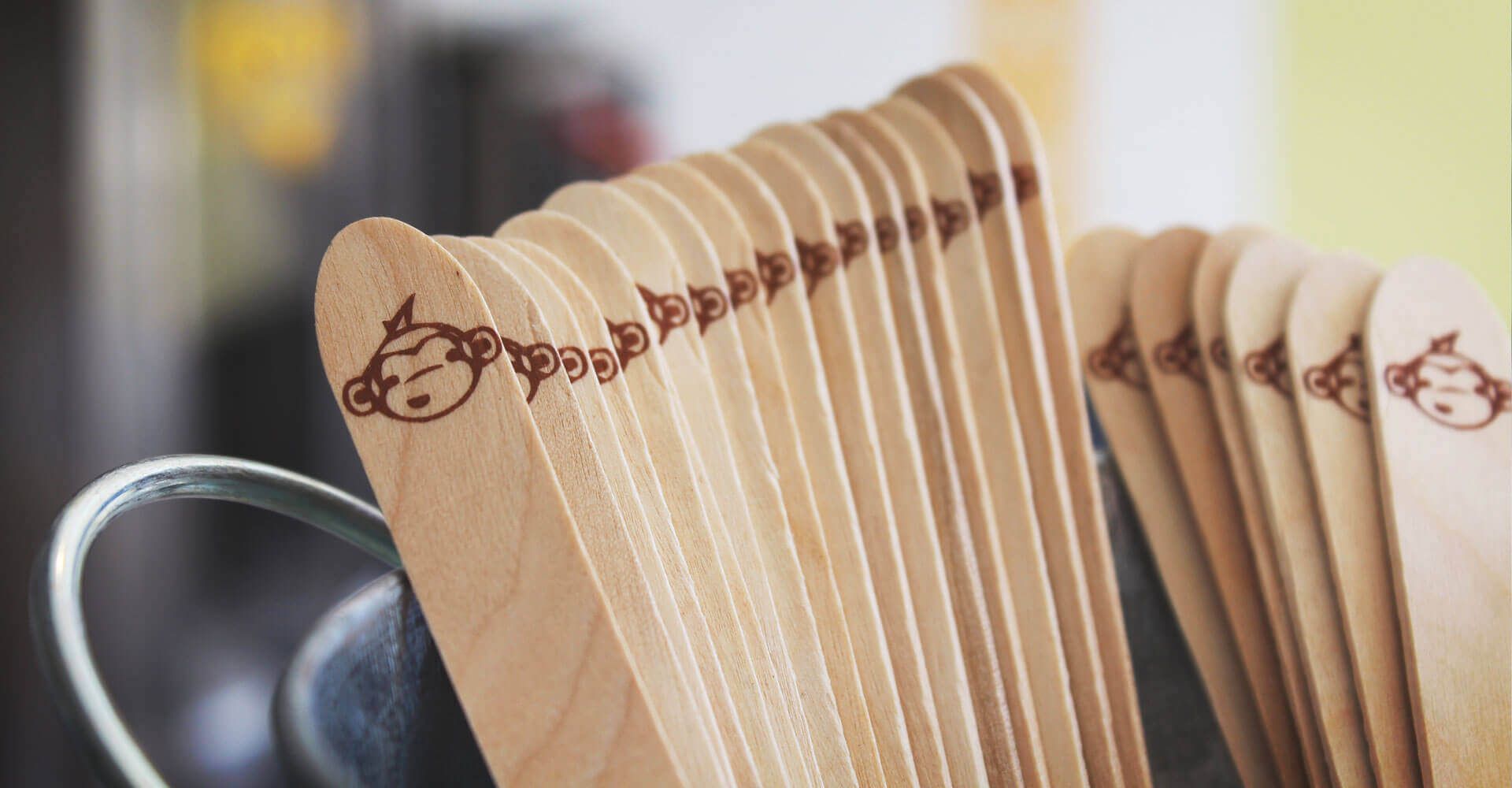 A bunch of wooden spoons are sitting in a metal bucket.