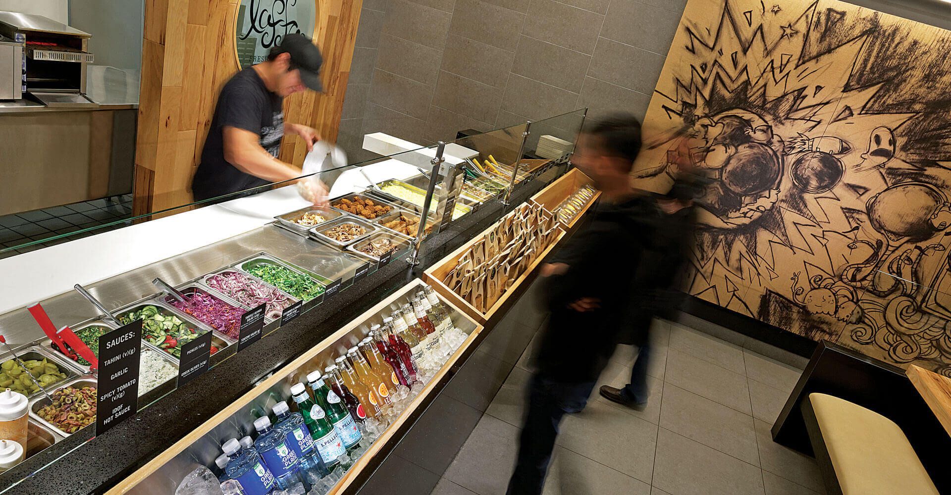 A man is preparing food at a counter in a restaurant.