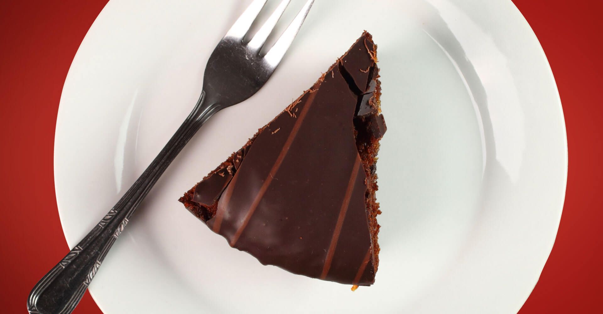 A slice of chocolate cake on a white plate with a fork