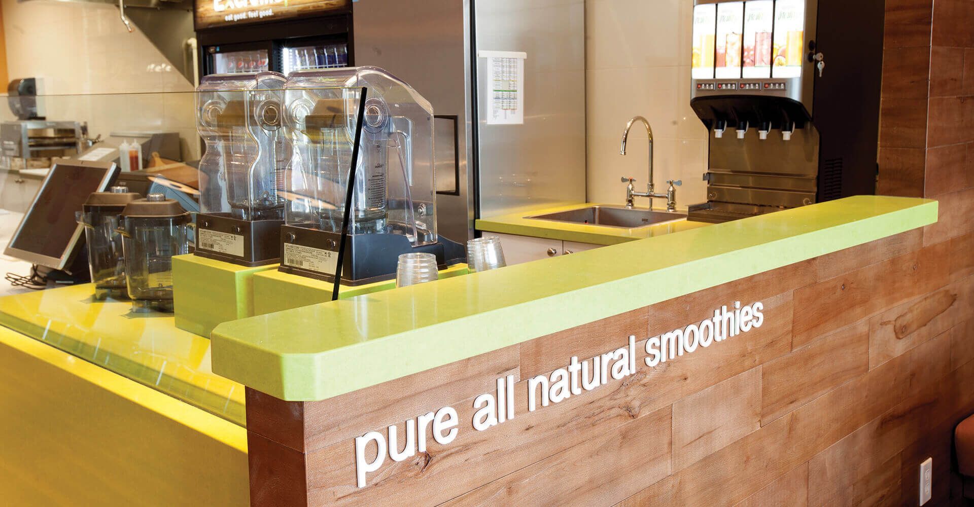 A counter in a restaurant that says pure all natural smoothies