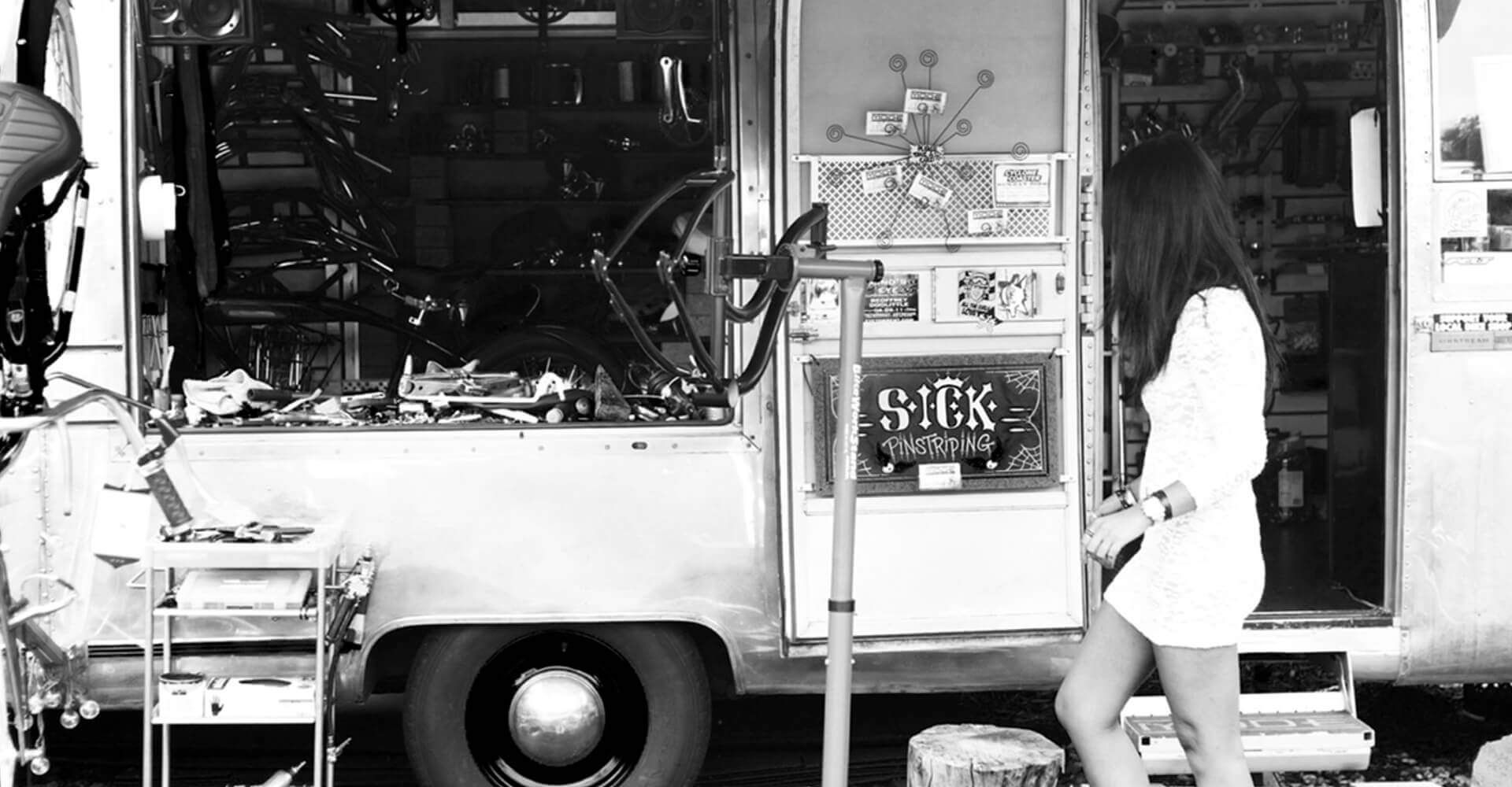 A woman is standing in front of a food truck.