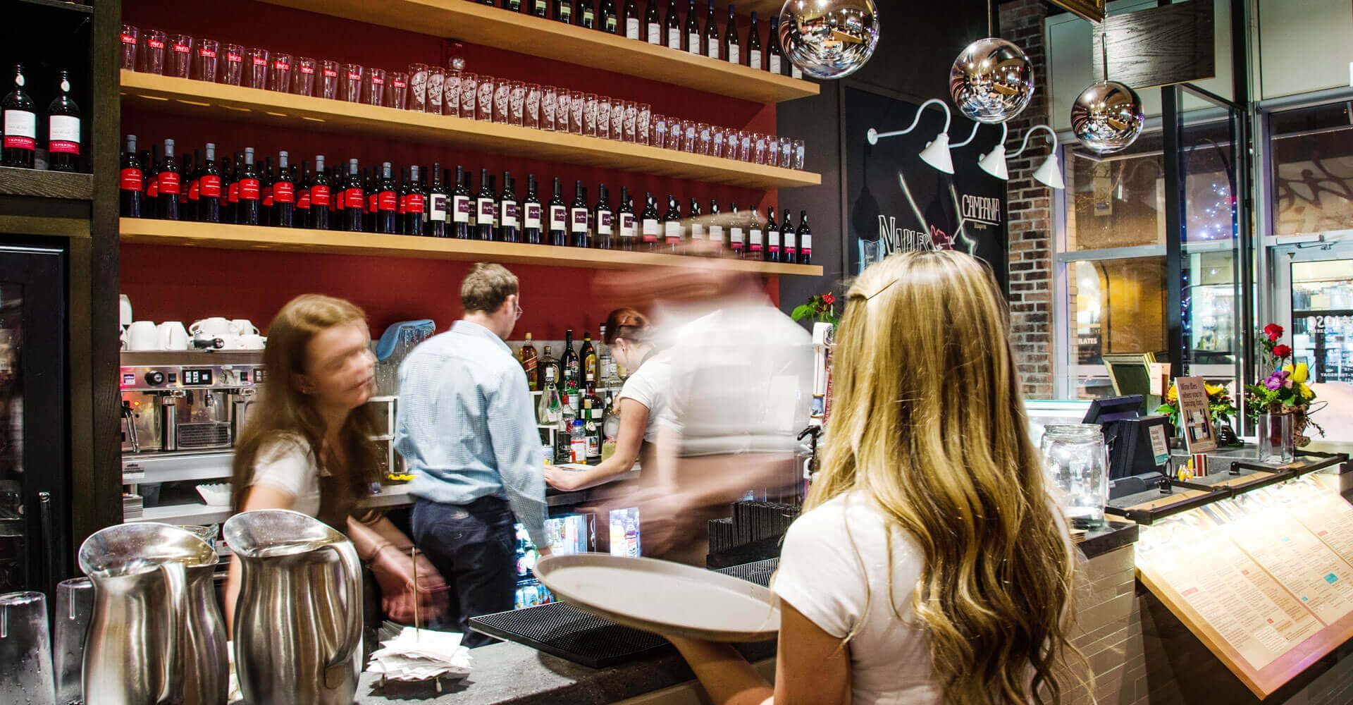 A woman is standing at a bar in a restaurant.