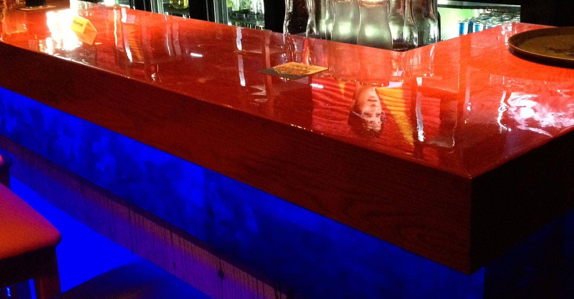 A bar with a red counter and blue lights behind it