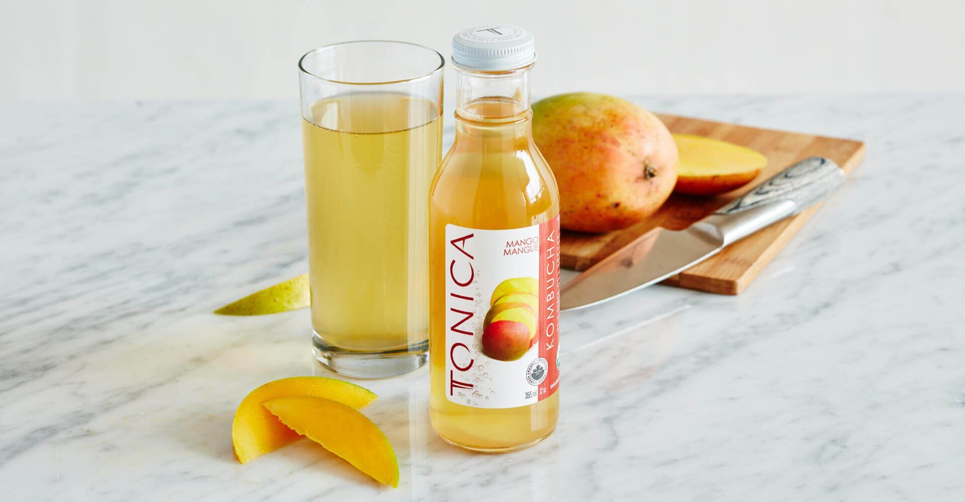There is a bottle of tonic next to a glass of tonic.
