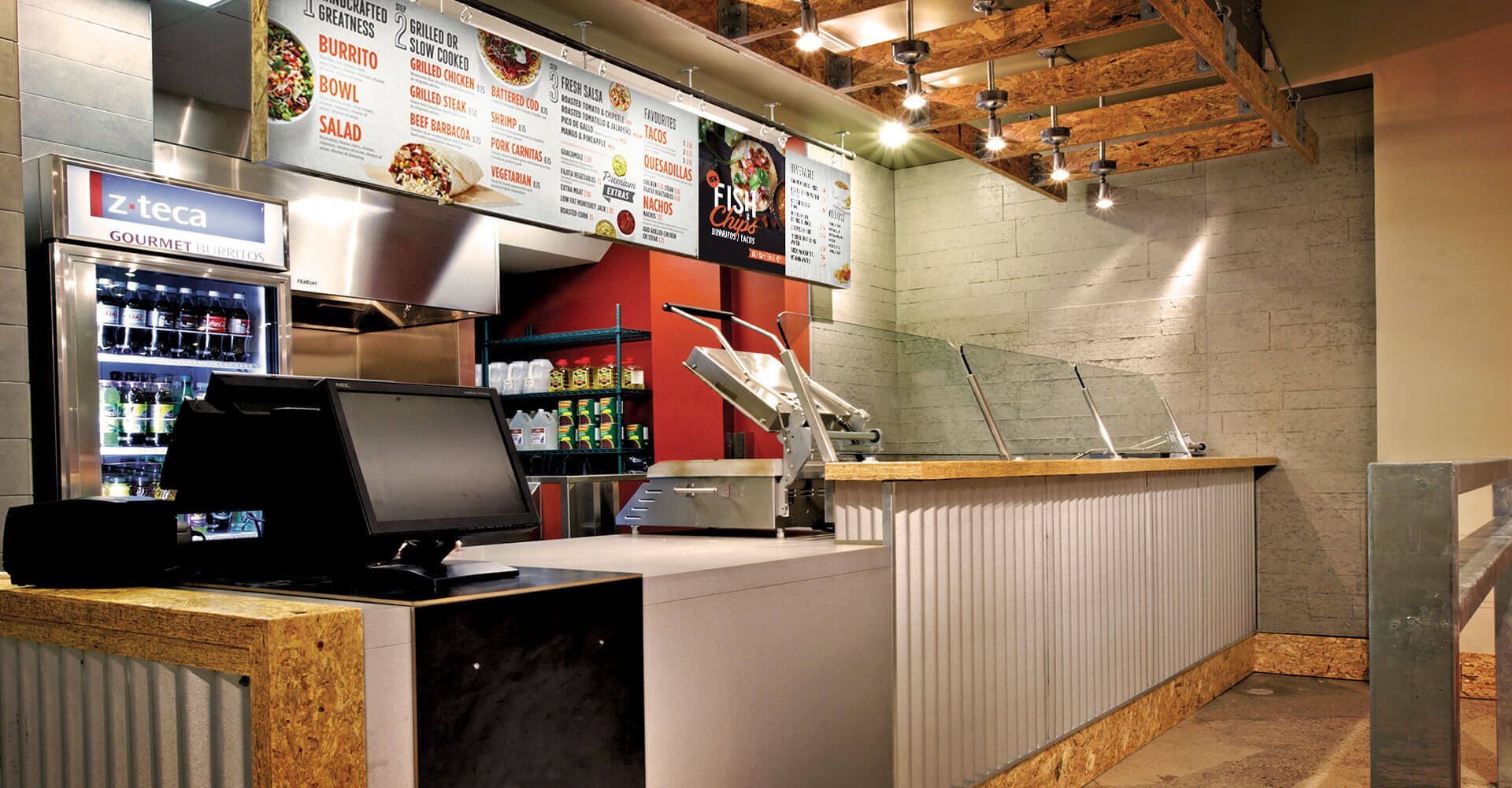 The inside of a restaurant with a counter and a refrigerator.