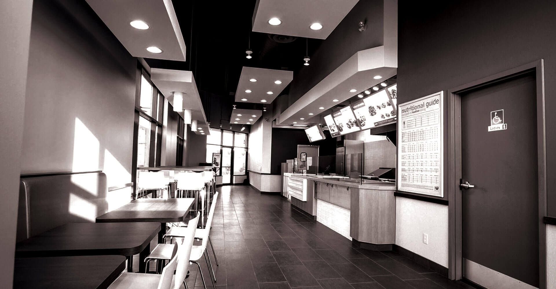 A black and white photo of a restaurant with tables and chairs.