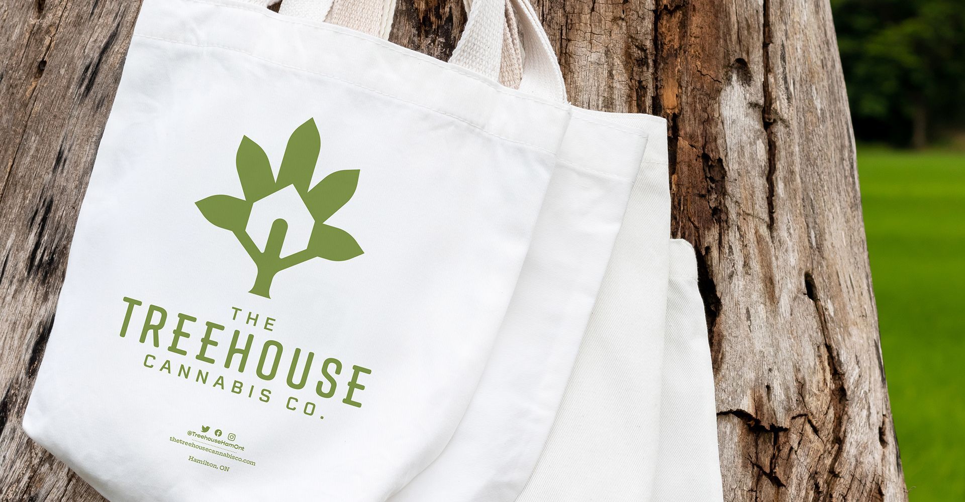 A treehouse tote bag is hanging from a tree