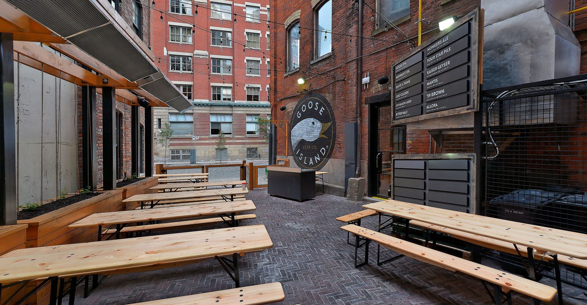 A row of wooden picnic tables and benches in a courtyard.