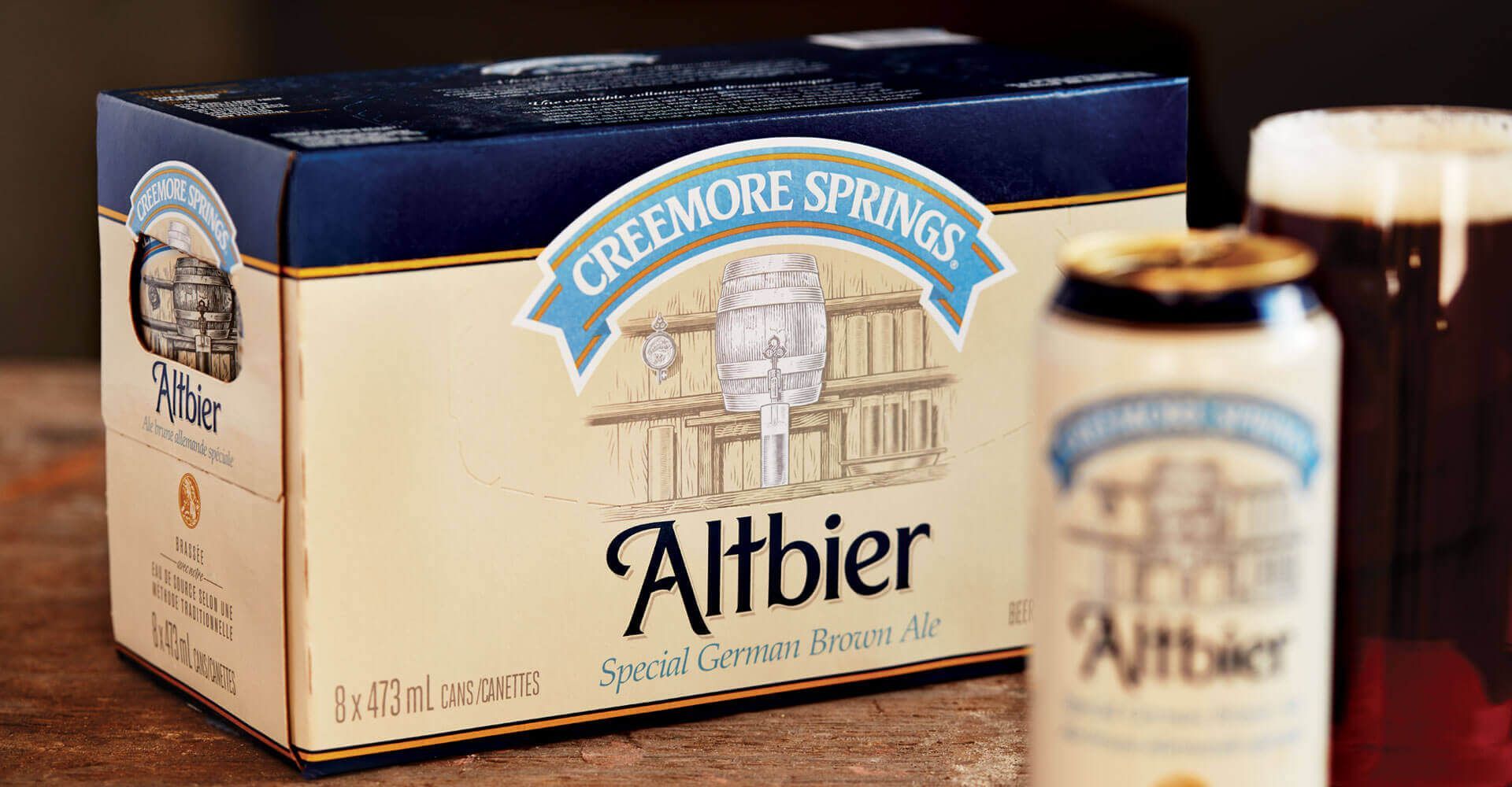 A box of creekmore springs altbier beer is sitting on a wooden table.