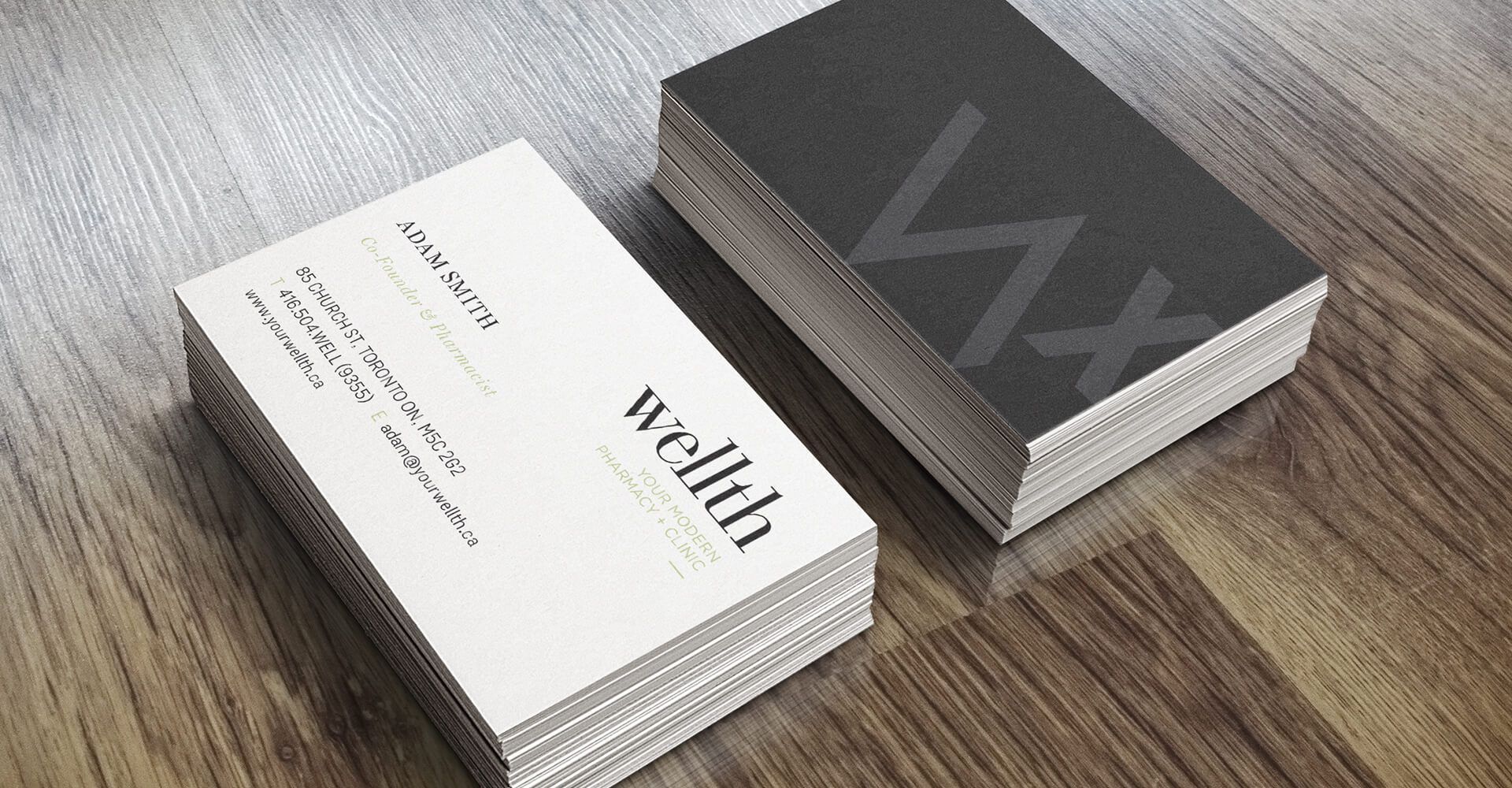 Two business cards are stacked on top of each other on a wooden table.