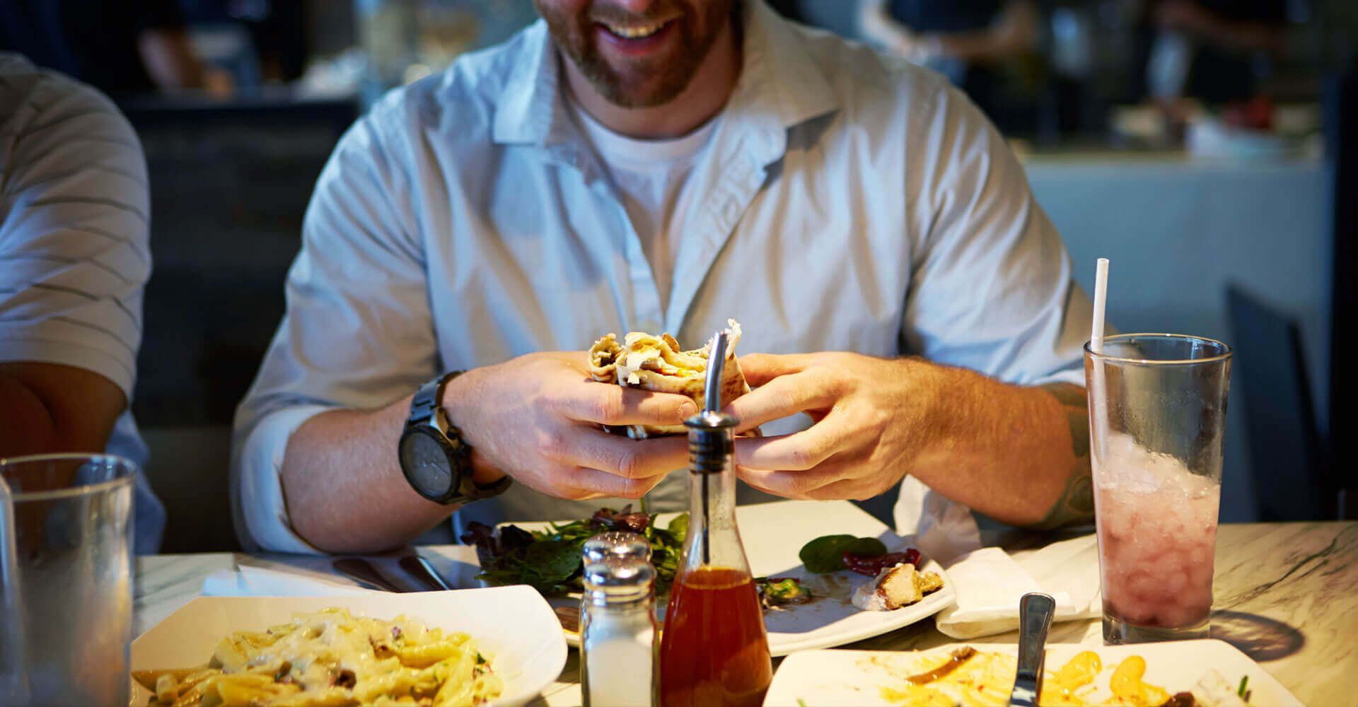 A man is sitting at a table eating a hamburger.