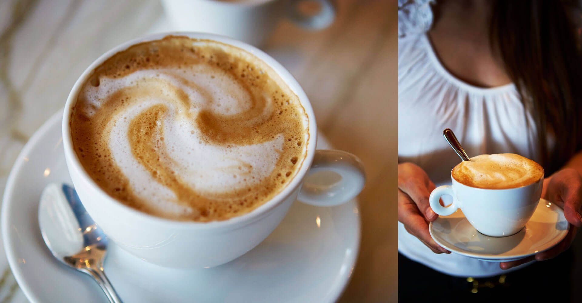 A woman is holding a cup of cappuccino with a spoon in her hand.