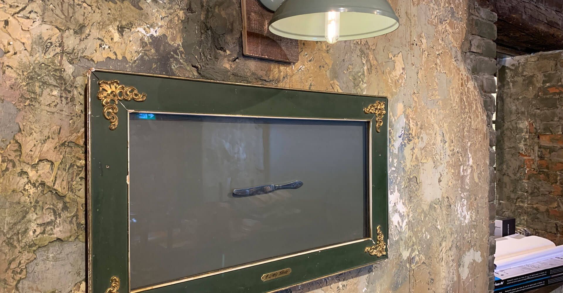 A television is hanging on a wall next to a lamp.