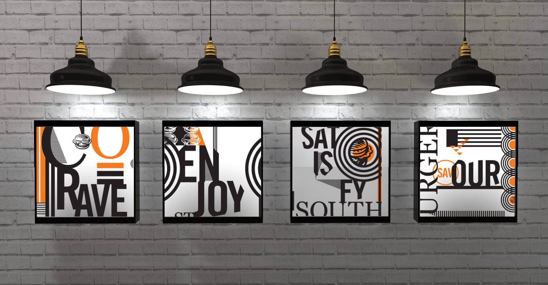 Four framed pictures are hanging on a brick wall.