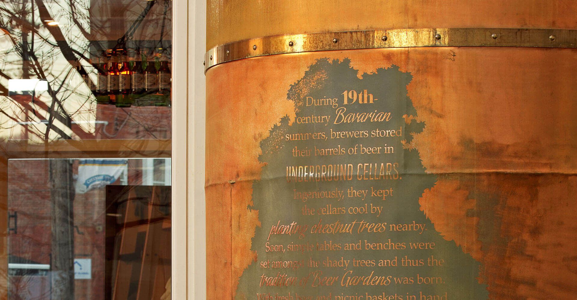 A large copper barrel is sitting in front of a window.