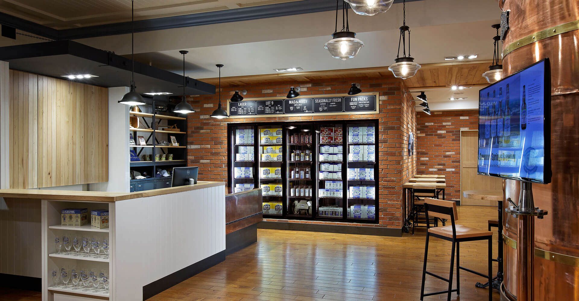A large room with a brick wall and a refrigerator.