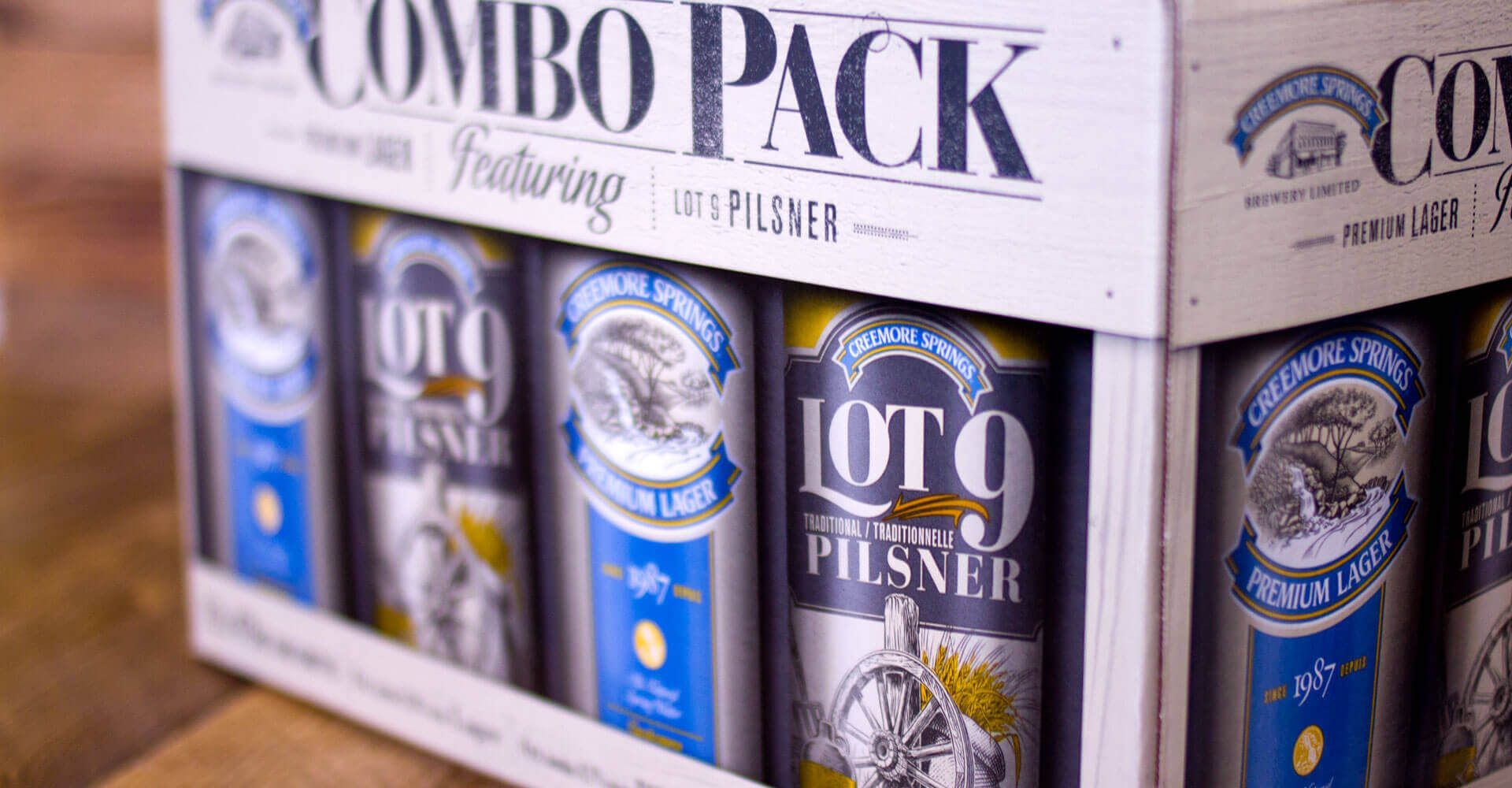 A combo pack of beer cans is sitting on a wooden table.