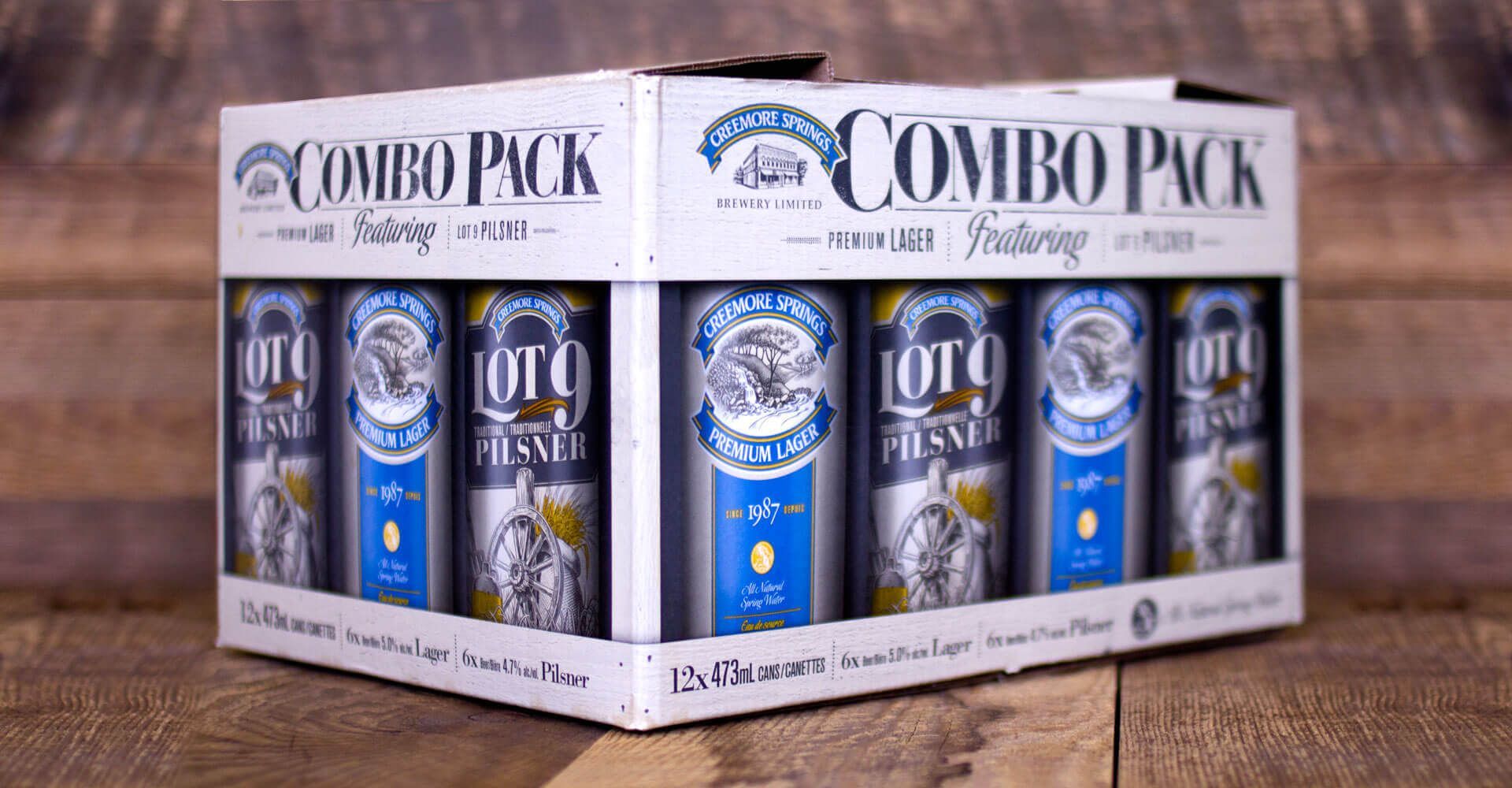 A combo pack of beer cans is sitting on a wooden table.